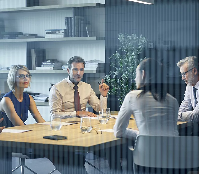 coworkers communicating at desk seen through glass